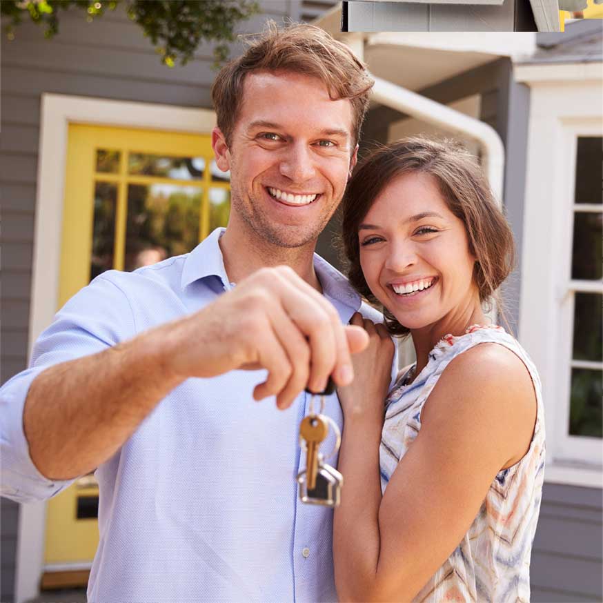 smiling couple with keys in front of their new home