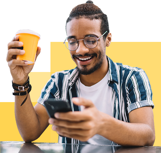 smiling young man looking at phone with coffee in hand
