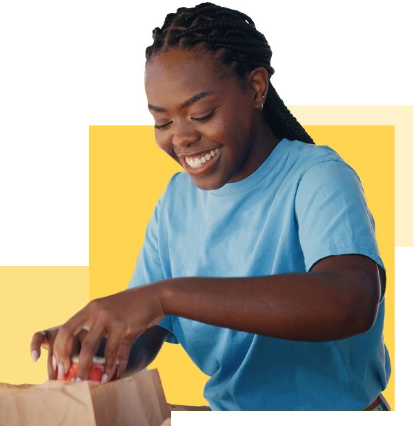 smiling woman in volunteer shirt packing grocery bag