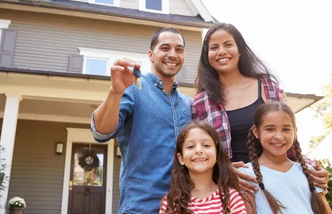 a smiling family standing in front of their new home