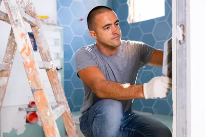 photo of a contractor laying tile in a bathroom
