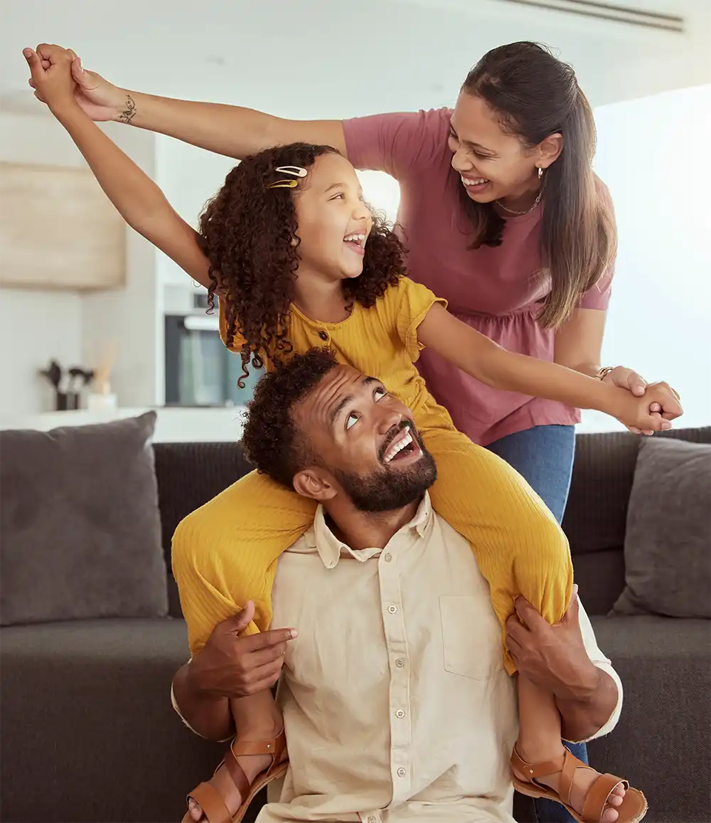photo of a mother, daughter, and father horsing around in the living room