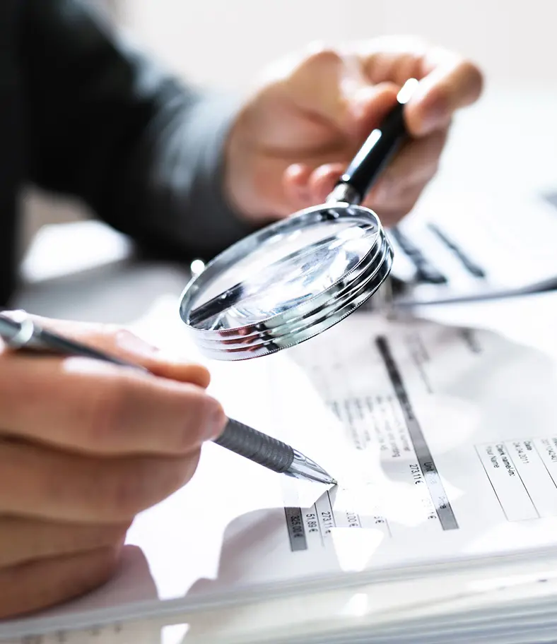 08-magnifying-glass-iStock-1335446674 photo of a person using a magnifying glass to examine documents