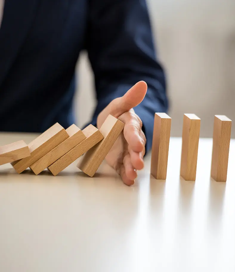 10-domino-concept-iStock-1224228790 photo of a person using their hand to stop dominoes from falling over